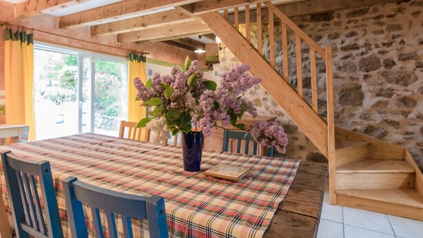 A dining area with a wooden staircase, a table with a plaid tablecloth, and a vase with flowers. - Cosy holiday home in Marsac with pool (Marsac)