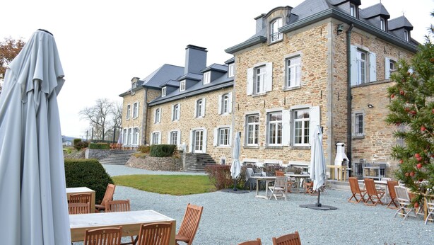 Een stenen gebouw met terras en parasols.