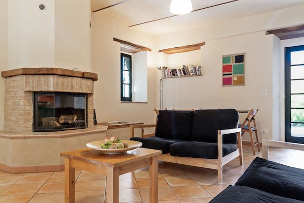 A living room with a fireplace, a black sofa, a wooden coffee table, and a bookshelf.