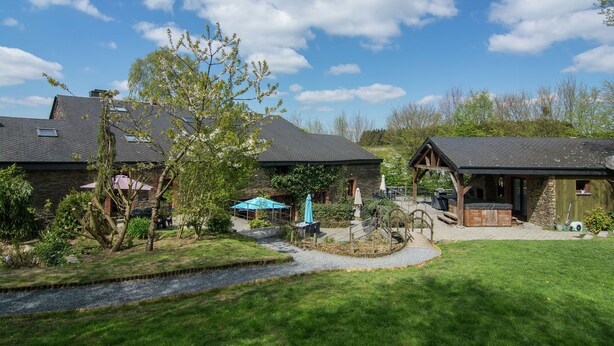 A residential property with a stone house, a wooden cabin, and a patio area with outdoor furniture.