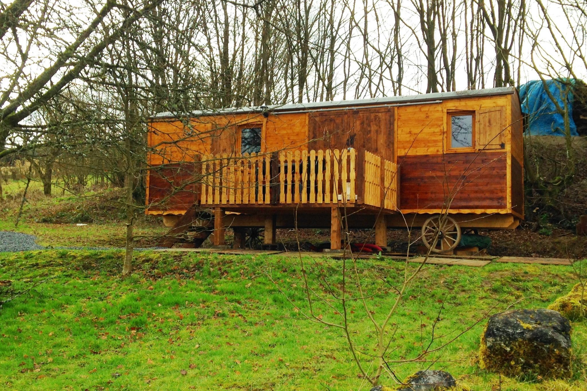 Een houten chalet met balkon, gelegen in een bebost gebied.