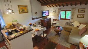 Un salon confortable avec un coin repas, un téléviseur et une fenêtre avec des rideaux.