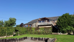 A two-story house with a balcony, surrounded by a well-maintained lawn and hedges. - Cottage in a well-equipped and comfortable farmhouse (Roy)