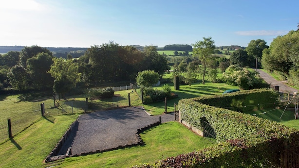 A landscaped garden with a paved area, pathways, and a variety of trees and shrubs. - Cottage in a well-equipped and comfortable farmhouse (Roy)