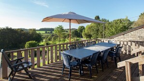 An outdoor deck with a table and chairs, a wooden railing, and a view of the countryside. - Cottage in a well-equipped and comfortable farmhouse (Roy)
