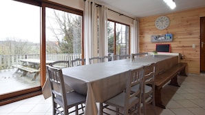 A dining area with a large table, chairs, and a view of the outdoors through large windows. - Cottage in a well-equipped and comfortable farmhouse (Roy)