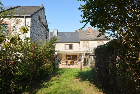 A stone building with a tiled patio and a small garden area. - Holiday Home in Izier with Roofed Terrace, Garden, Parking (Izier)