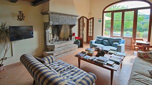 A cozy living room with a fireplace, sofas, and a television.