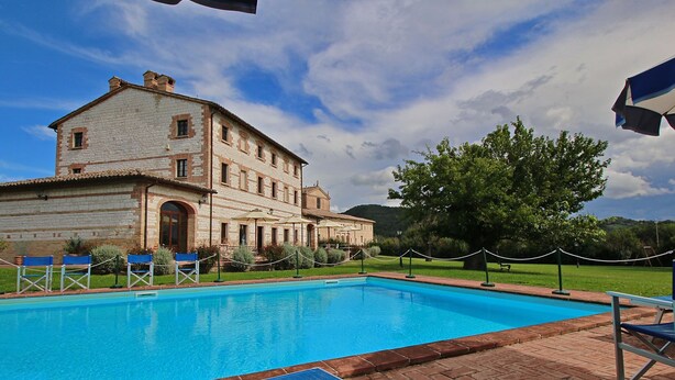 A swimming pool with lounge chairs and a building with a tiled roof.