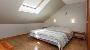 A bedroom with a skylight, a bed with a striped bedspread, wooden flooring, and two wall-mounted lights. - Stunning Cottage with Terrace in Manhay (Vaux-Chavanne)