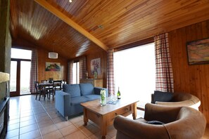 A wooden interior with a sofa, armchairs, a dining table, and a painting on the wall. - Holiday Home in Tenneville by Ourthe River (Tenneville)