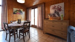 Een kamer met houten lambrisering, een voor vier personen gedekte eettafel, een dressoir en twee schilderijen aan de wanden.