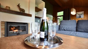 A bottle of wine on a tray with glasses, a fireplace, a sofa, and a deer decoration.