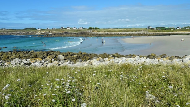 A coastal beach with a rocky shoreline, grassy areas, and houses in the background. - Holiday home with private pool (Plouguin)