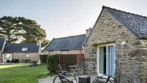 A stone cottage with a patio area featuring outdoor furniture and a view of the surrounding landscape. - Holiday home with private pool (Plouguin)