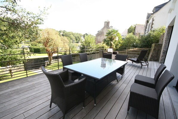 A covered outdoor patio with a rectangular table and six wicker chairs.