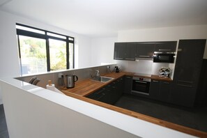 A modern kitchen with a wooden countertop, stainless steel appliances, and dark cabinetry.