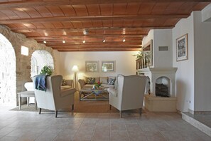 A cozy living room with a stone wall, wooden ceiling, and a fireplace.