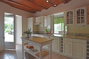 A kitchen with a central island, white cabinetry, and a view of the outdoors.
