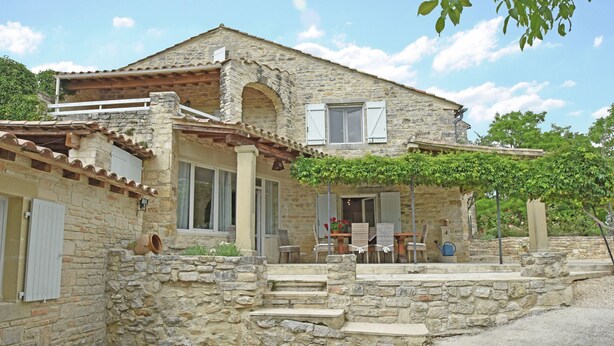 A stone house with a balcony, a porch with chairs, and a small table. - Two guest houses with private pool (Saint Privas de Champclos)