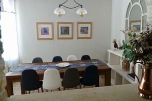 A dining area with a wooden table, chairs, and framed artwork on the wall.