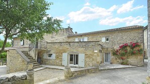 A stone building with a staircase leading to a door, a small window, and a flower box. - Two guest houses with private pool (Saint Privas de Champclos)