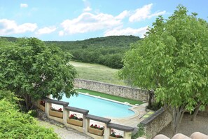 A swimming pool with a stone wall and a grassy area in the background.