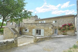 A stone building with a staircase leading to a door, a small window, and a flower box.