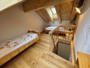 Pequeño dormitorio abuhardinado de madera con dos camas individuales, una escalera de madera y un tragaluz.