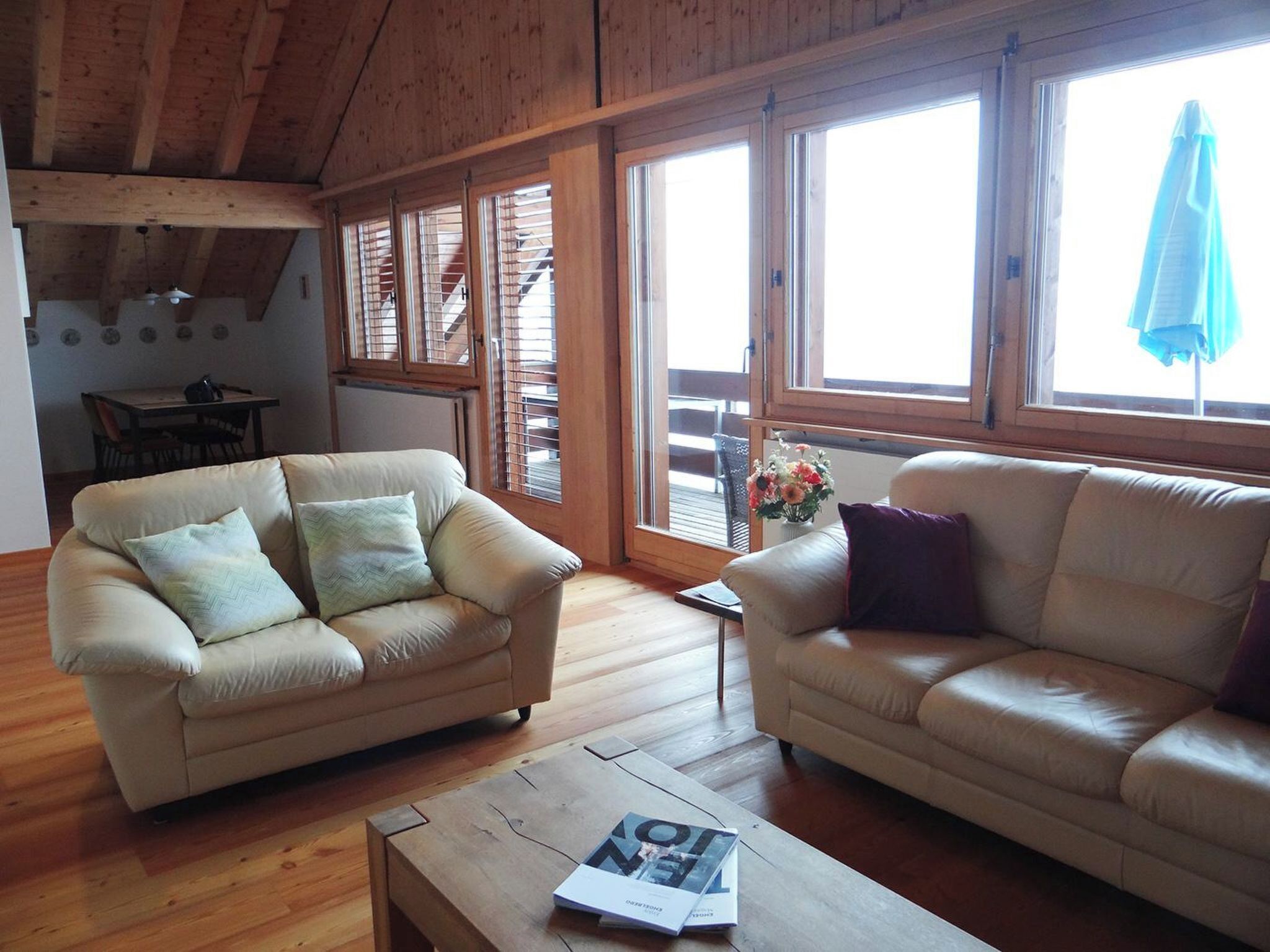 A cozy living room with two sofas, a coffee table, and large windows with blinds.
