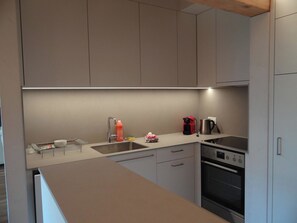 A modern kitchen with a built-in oven, a sink, and a coffee maker.