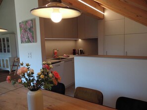 Une cuisine moderne avec des meubles en bois, une table à manger avec des chaises et un vase de fleurs.