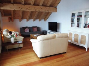 Una sala de estar con un sofá, una mesa de centro, un televisor y una estantería.
