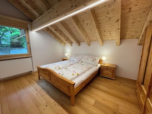 Een slaapkamer met houten frame, een bed, nachtkastjes en een raam.