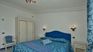 A bedroom with a bed, a chair, a wardrobe, and two bedside tables. - Belvilla by OYO Oasi Blu (Praiano)