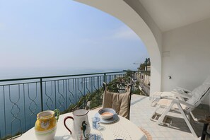 Ein Balkon mit Tisch für zwei Personen, mit Blick auf eine schöne Meereslandschaft.