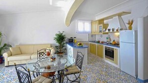 A compact living space with a dining area, kitchenette, and a sofa. - Belvilla by OYO Oasi Blu (Praiano)