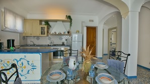 A dining area with a glass table, chairs, and a decorative vase. - Belvilla by OYO Oasi Blu (Praiano)