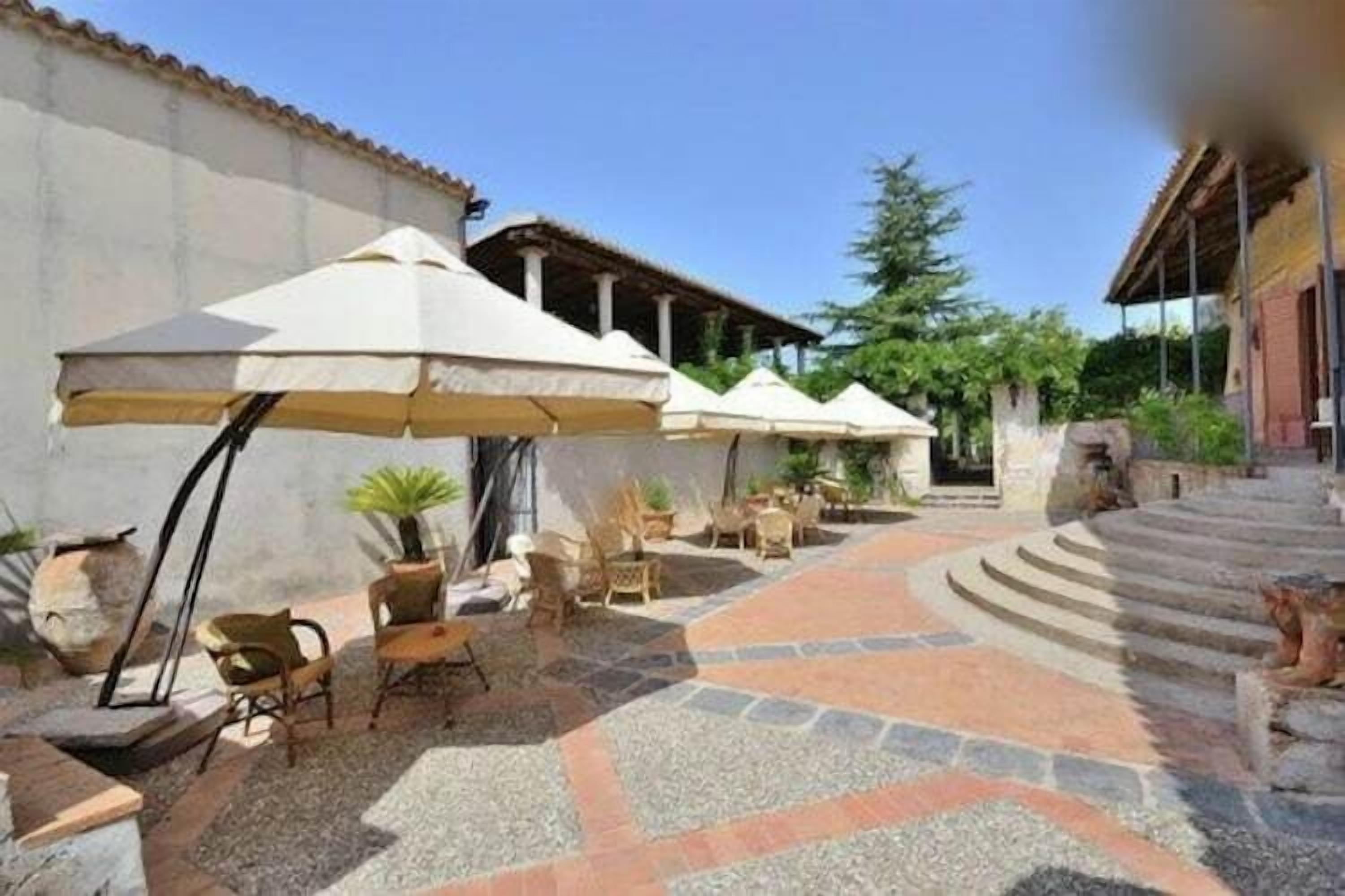 A courtyard with outdoor seating, umbrellas, and stone flooring.