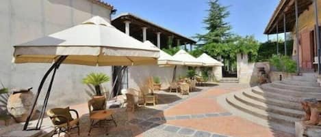 A courtyard with outdoor seating, umbrellas, and stone flooring.