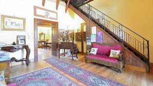 A spacious living room with a wooden staircase, a sofa with pink cushions, and a large rug. - Mansion in Parghelia near Coast of the Gods (Parghelia)