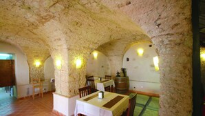 A dining area with stone arches, tables with white tablecloths, wooden chairs, and a barrel. - Mansion in Parghelia near Coast of the Gods (Parghelia)