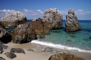 Une plage avec de grandes formations rocheuses et une eau turquoise cristalline.