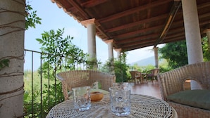 A covered outdoor seating area with wicker furniture and two glasses on a woven table. - Mansion in Parghelia near Coast of the Gods (Parghelia)
