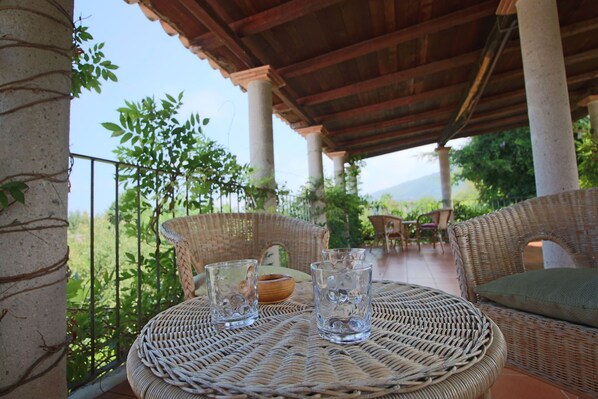 A covered outdoor seating area with wicker furniture and two glasses on a woven table.