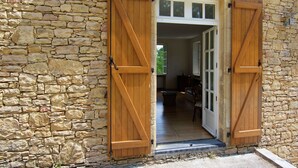 A stone building with wooden shutters and a doorway leading to an interior space.