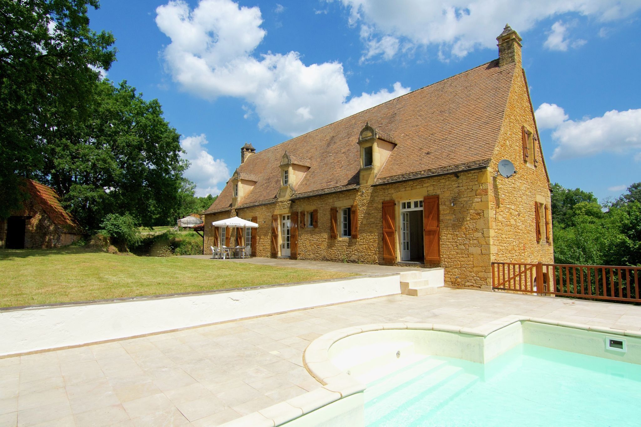 Ein Steinhaus mit Swimmingpool, Rasenfläche und Terrassenbereich.