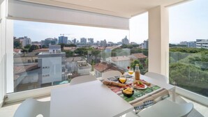 Et moderne spiseområde med et bord dækket til to, med udsigt over en by og grønne områder.