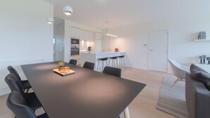 A modern kitchen with white cabinets, a central island, and bar stools.
