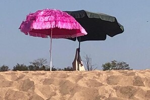 A pink and black umbrella on a sandy surface.